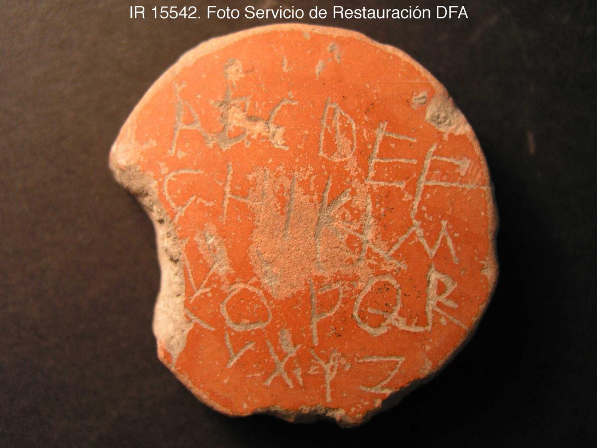 Pieza IR 15542 con abecedario Pieza cerámica circular IR 15542 de Iruña-Veleia con un abecedario y otros signos incisos.